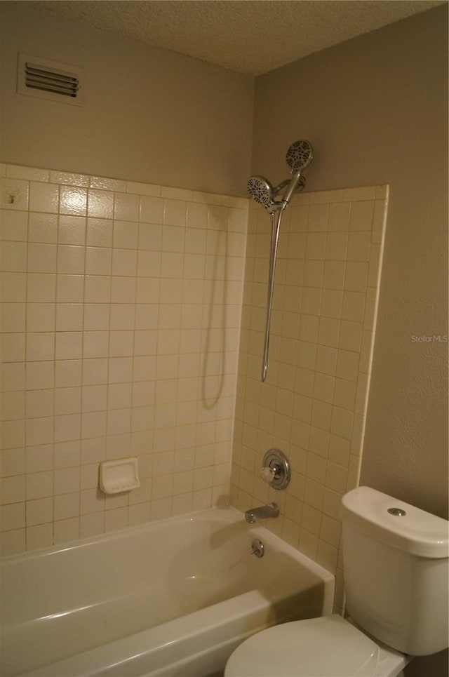 bathroom featuring visible vents, toilet, bathtub / shower combination, and a textured ceiling