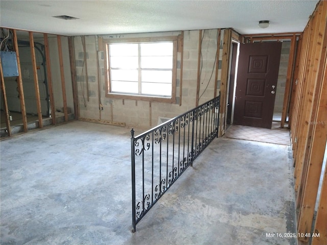 interior space featuring electric panel, unfinished concrete floors, and a textured ceiling