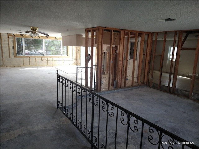 interior space with a textured ceiling and ceiling fan