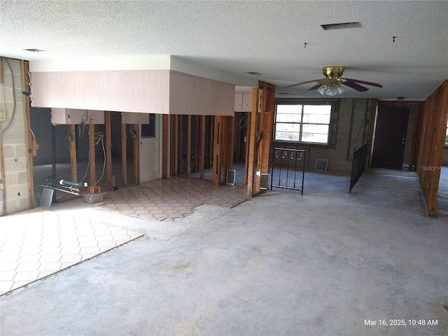 interior space featuring a textured ceiling, unfinished concrete floors, visible vents, and ceiling fan