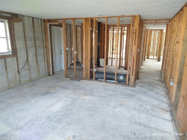 miscellaneous room with a textured ceiling and concrete block wall