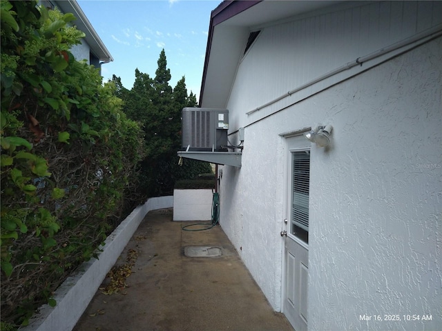 view of side of property with cooling unit and stucco siding