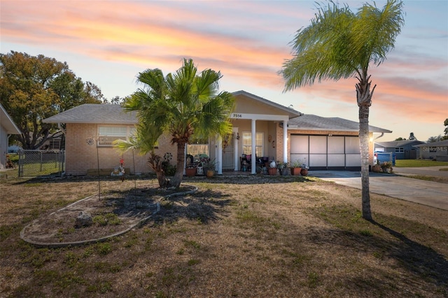 view of front of house featuring fence, concrete driveway, a front yard, an attached garage, and brick siding