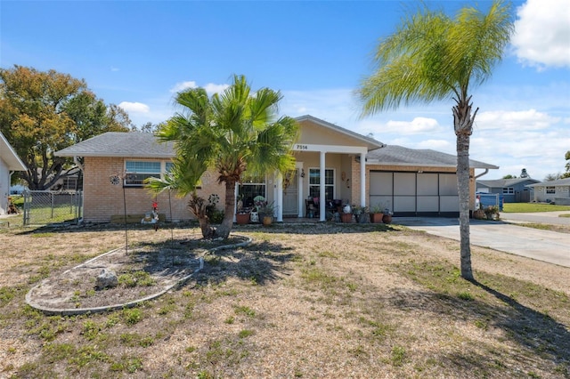 single story home featuring fence, an attached garage, covered porch, concrete driveway, and brick siding