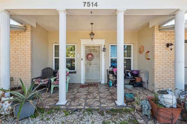 view of exterior entry with brick siding and stucco siding