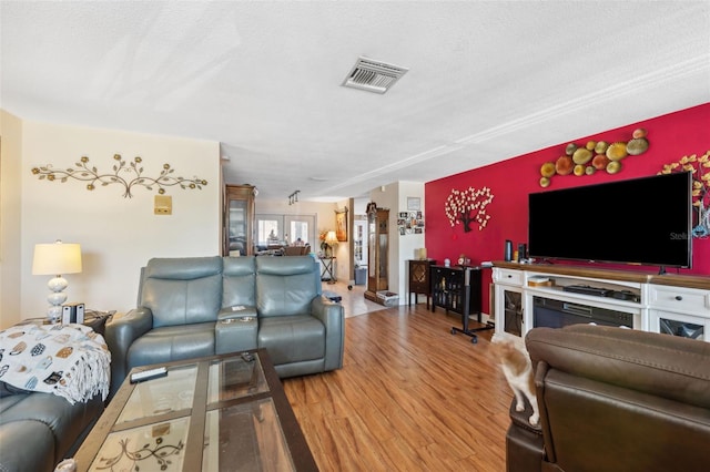 living room featuring visible vents, a textured ceiling, and wood finished floors