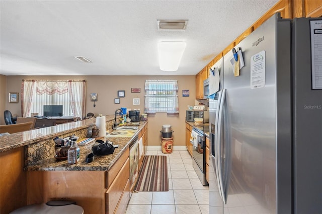 kitchen featuring visible vents, a sink, plenty of natural light, stainless steel appliances, and light tile patterned floors