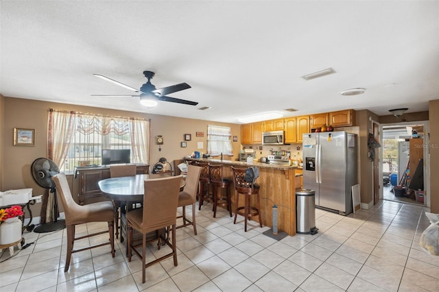 dining space with light tile patterned floors, visible vents, a healthy amount of sunlight, and a ceiling fan