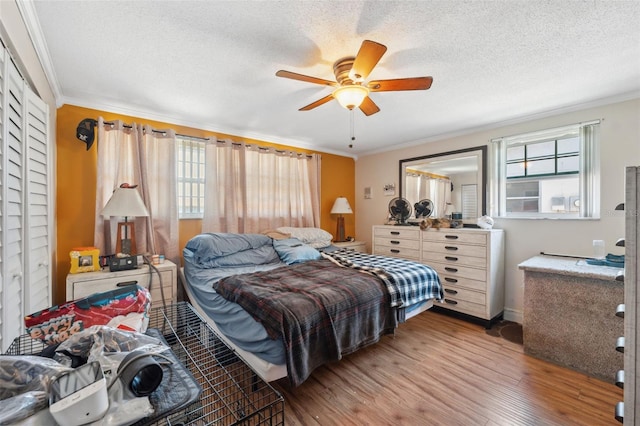 bedroom with a textured ceiling, wood finished floors, and ornamental molding