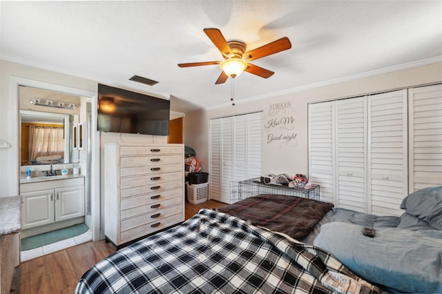 bedroom with visible vents, a sink, crown molding, and wood finished floors