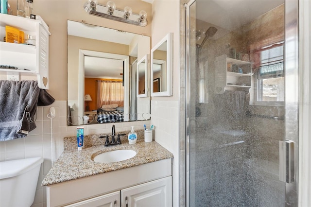 bathroom featuring a shower stall, tile walls, toilet, vanity, and ensuite bath