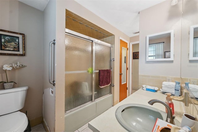 full bath with toilet, vanity, and bath / shower combo with glass door