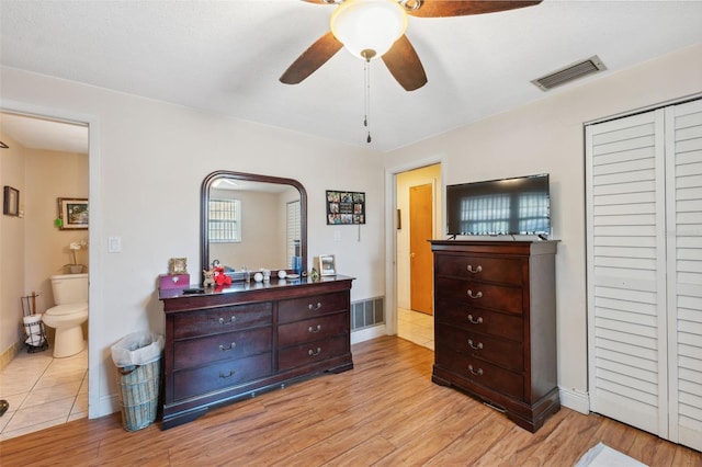 bedroom with a closet, light wood-style floors, visible vents, and ensuite bathroom