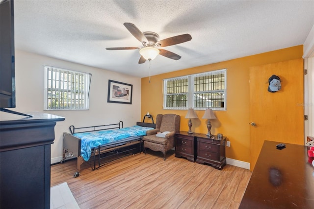 bedroom with a ceiling fan, light wood-style floors, baseboards, and a textured ceiling