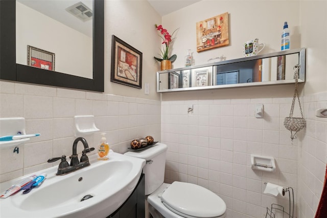 bathroom with a sink, visible vents, toilet, and a wainscoted wall