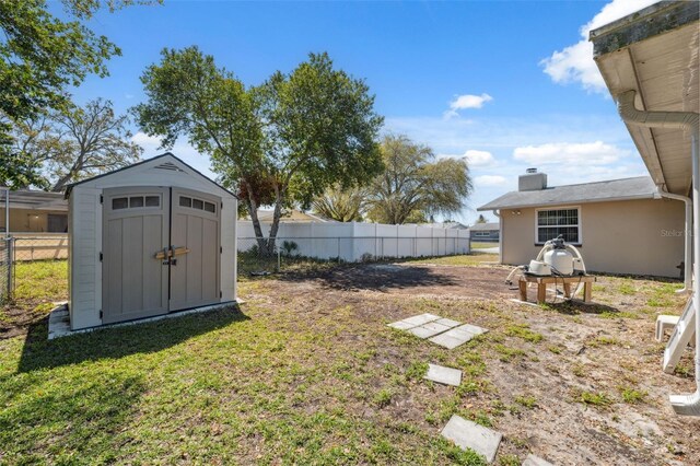 view of yard featuring an outdoor structure, a storage unit, and fence