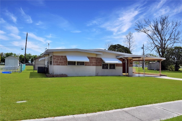 view of front of property featuring a carport, fence, a front lawn, and central AC