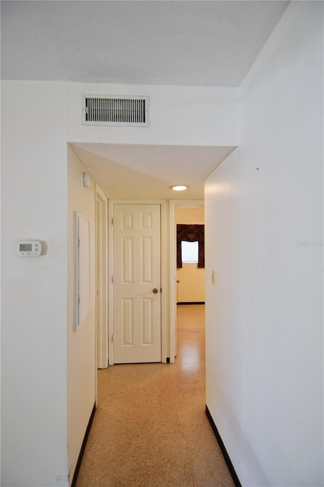 hall featuring visible vents, light floors, and baseboards