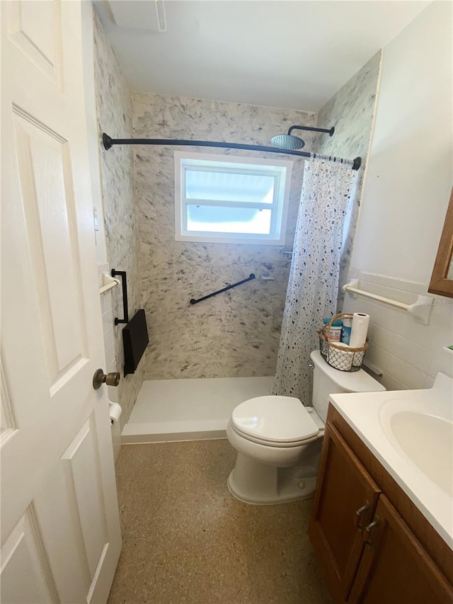 bathroom with vanity, toilet, tile walls, and a shower stall