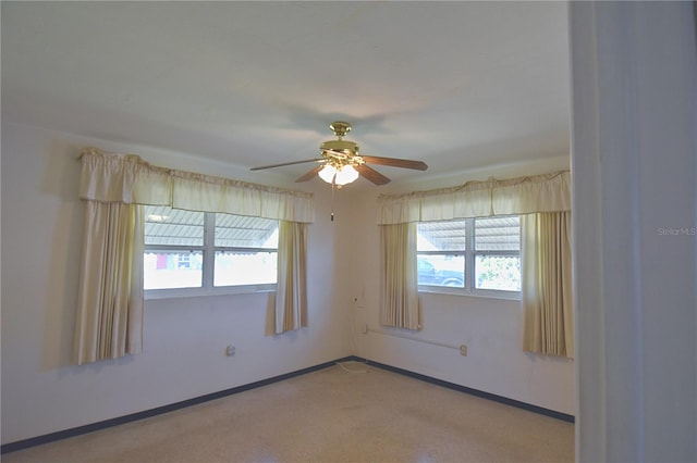 carpeted spare room with a ceiling fan and baseboards