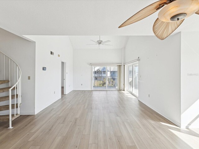 5557 Sea Forest Dr Unit 318, New Port Richey, FL 34652 - unfurnished living room featuring a ceiling fan, light wood-style floors, stairway, and lofted ceiling