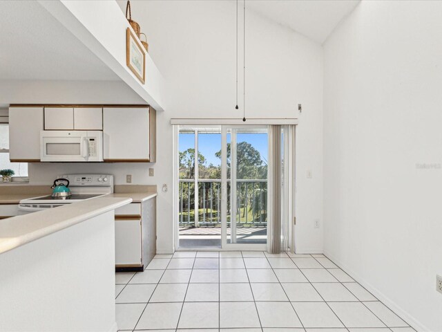 5557 Sea Forest Dr Unit 318, New Port Richey, FL 34652 - kitchen with white cabinetry, light countertops, white appliances, light tile patterned flooring, and a towering ceiling