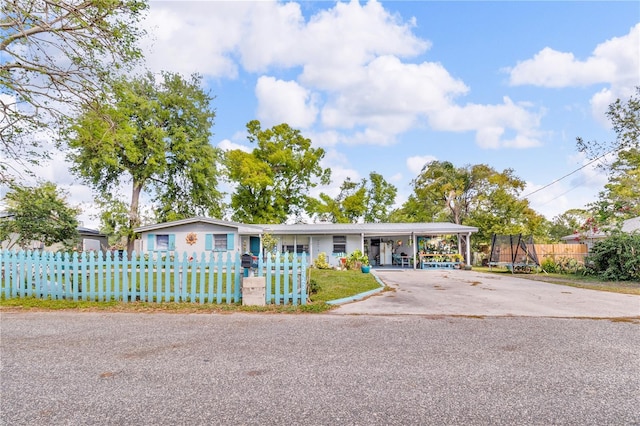 ranch-style home with a fenced front yard, concrete driveway, and a carport