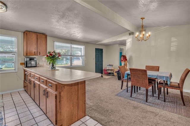 kitchen with light carpet, brown cabinets, a peninsula, an inviting chandelier, and light countertops