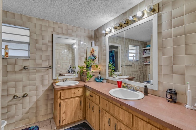 full bathroom with a sink, a textured ceiling, tile walls, and a healthy amount of sunlight