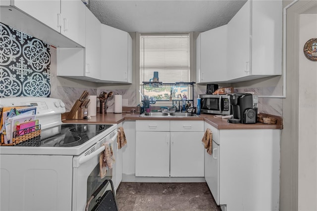 kitchen featuring stainless steel microwave, white cabinetry, electric stove, a textured ceiling, and a sink