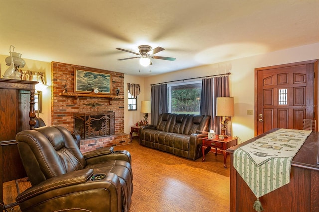 living area featuring ceiling fan, a brick fireplace, and wood finished floors