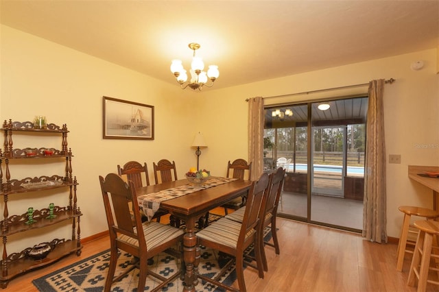 dining room featuring light wood-style flooring, an inviting chandelier, and baseboards