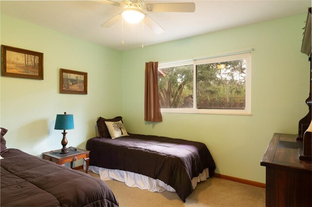 bedroom with light colored carpet, baseboards, and a ceiling fan
