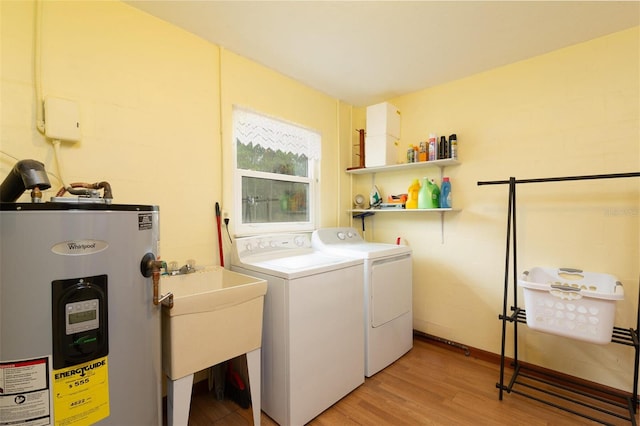 laundry area with laundry area, water heater, a sink, light wood finished floors, and washing machine and dryer