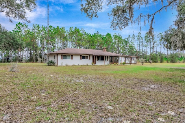 single story home featuring a carport, a front lawn, and a chimney