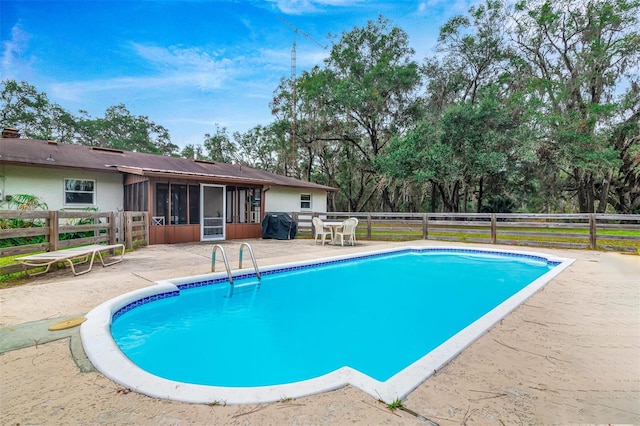 view of swimming pool featuring a fenced in pool, a grill, a patio area, a sunroom, and fence