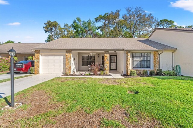 ranch-style home featuring a front yard, driveway, an attached garage, covered porch, and stone siding