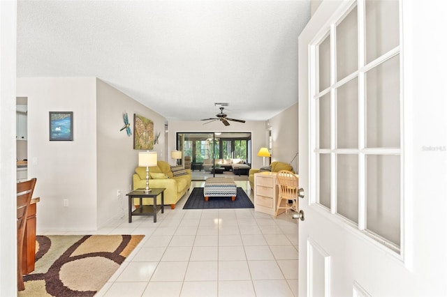living room with a textured ceiling, light tile patterned floors, visible vents, and ceiling fan