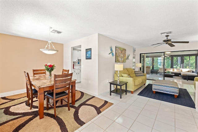 dining room with light tile patterned floors, visible vents, a textured ceiling, and ceiling fan