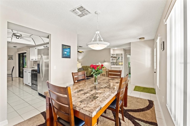 dining area with visible vents, a textured ceiling, light tile patterned floors, baseboards, and ceiling fan