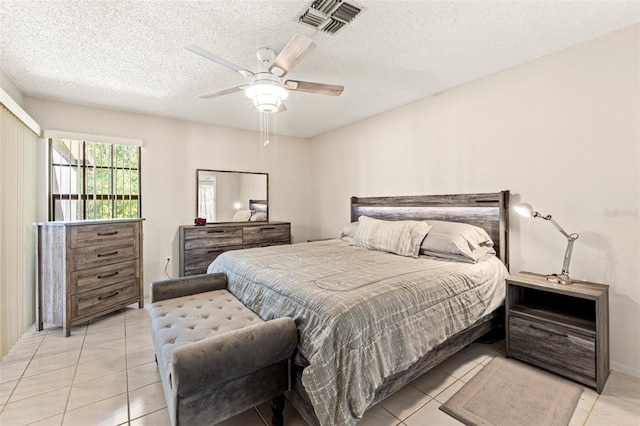 bedroom with light tile patterned floors, a ceiling fan, visible vents, and a textured ceiling