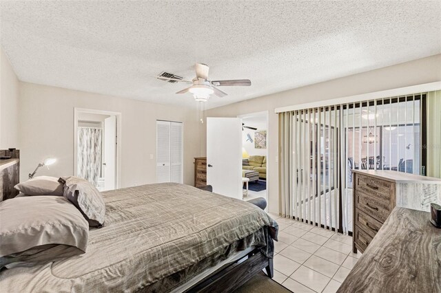 bedroom featuring visible vents, a textured ceiling, a closet, light tile patterned floors, and ceiling fan