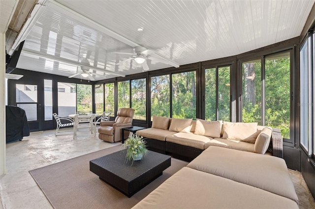 sunroom with an outdoor living space, a wealth of natural light, a ceiling fan, and concrete flooring