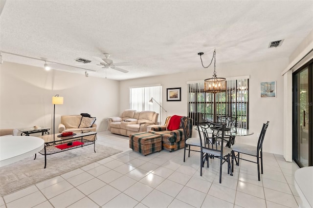 dining area with light tile patterned floors, visible vents, ceiling fan with notable chandelier, and a textured ceiling