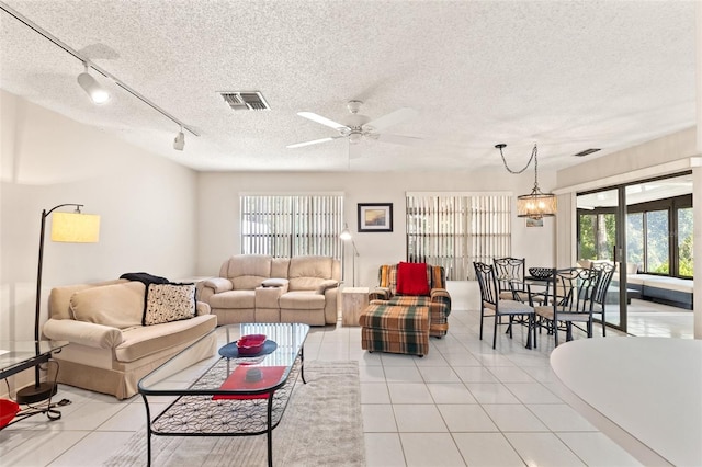 living room with light tile patterned flooring, a ceiling fan, visible vents, and a textured ceiling