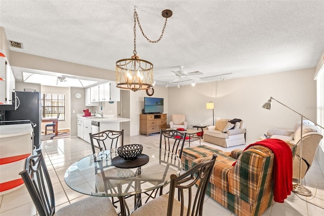 dining area featuring visible vents, track lighting, light tile patterned floors, ceiling fan with notable chandelier, and a textured ceiling
