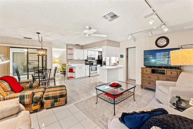 living area featuring light tile patterned floors, visible vents, a textured ceiling, and a ceiling fan