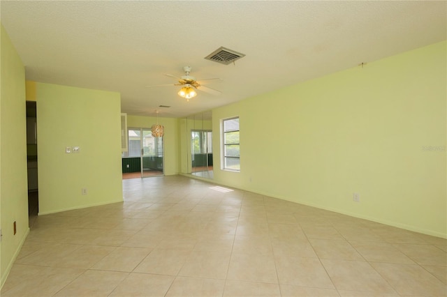 spare room featuring visible vents, baseboards, ceiling fan, and light tile patterned flooring