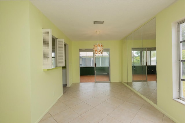 unfurnished room featuring light tile patterned floors, visible vents, an inviting chandelier, and a healthy amount of sunlight