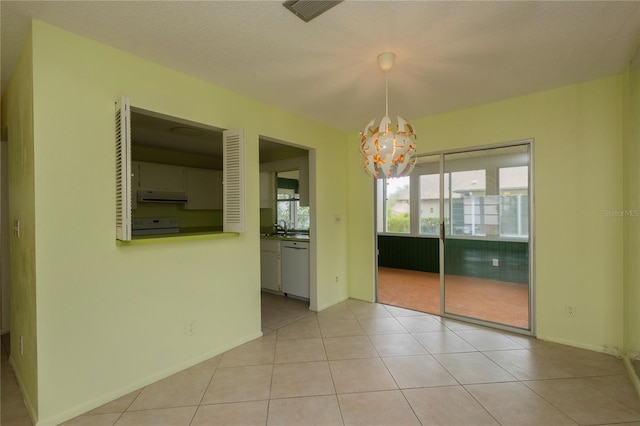 unfurnished dining area featuring visible vents, a notable chandelier, a sink, light tile patterned flooring, and baseboards